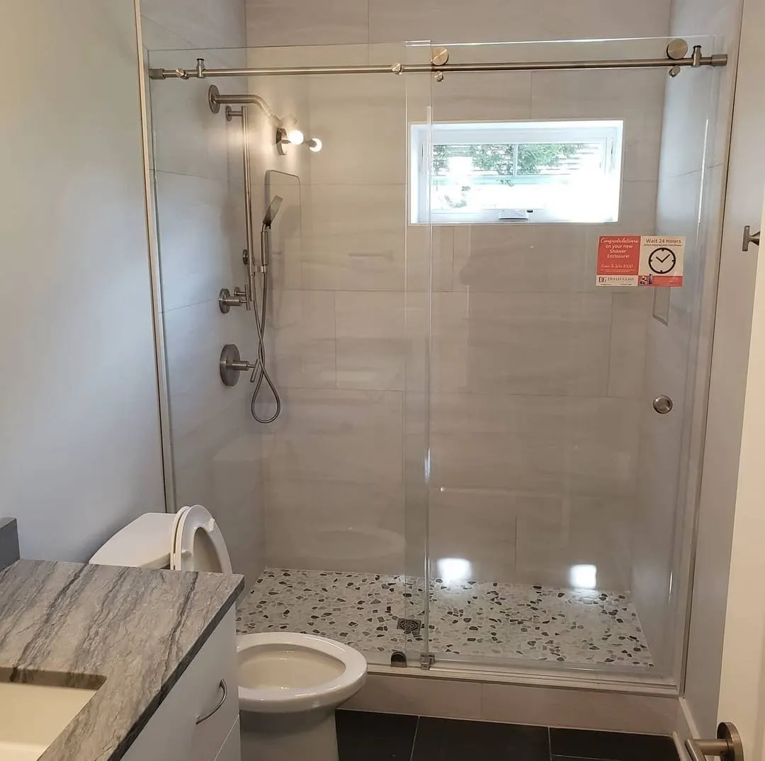 Bathroom with glass shower, gray tile, and pebble shower floor