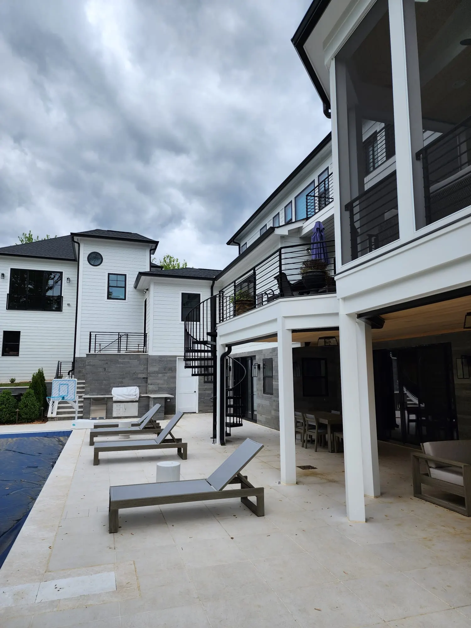 Rear patio with lounge chairs, spiral staircase, and covered seating area
