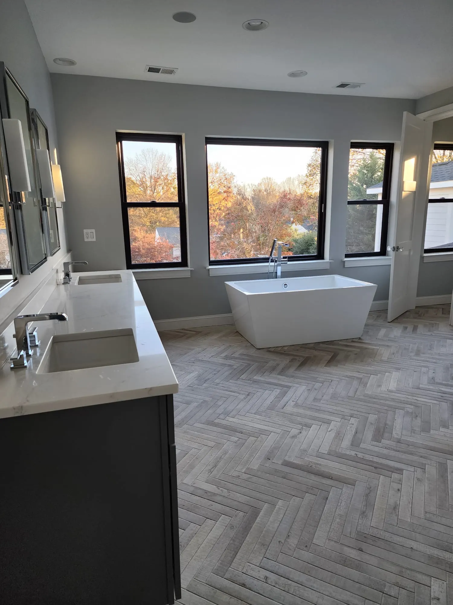 Primary bathroom with freestanding tub, double vanity, and herringbone floor