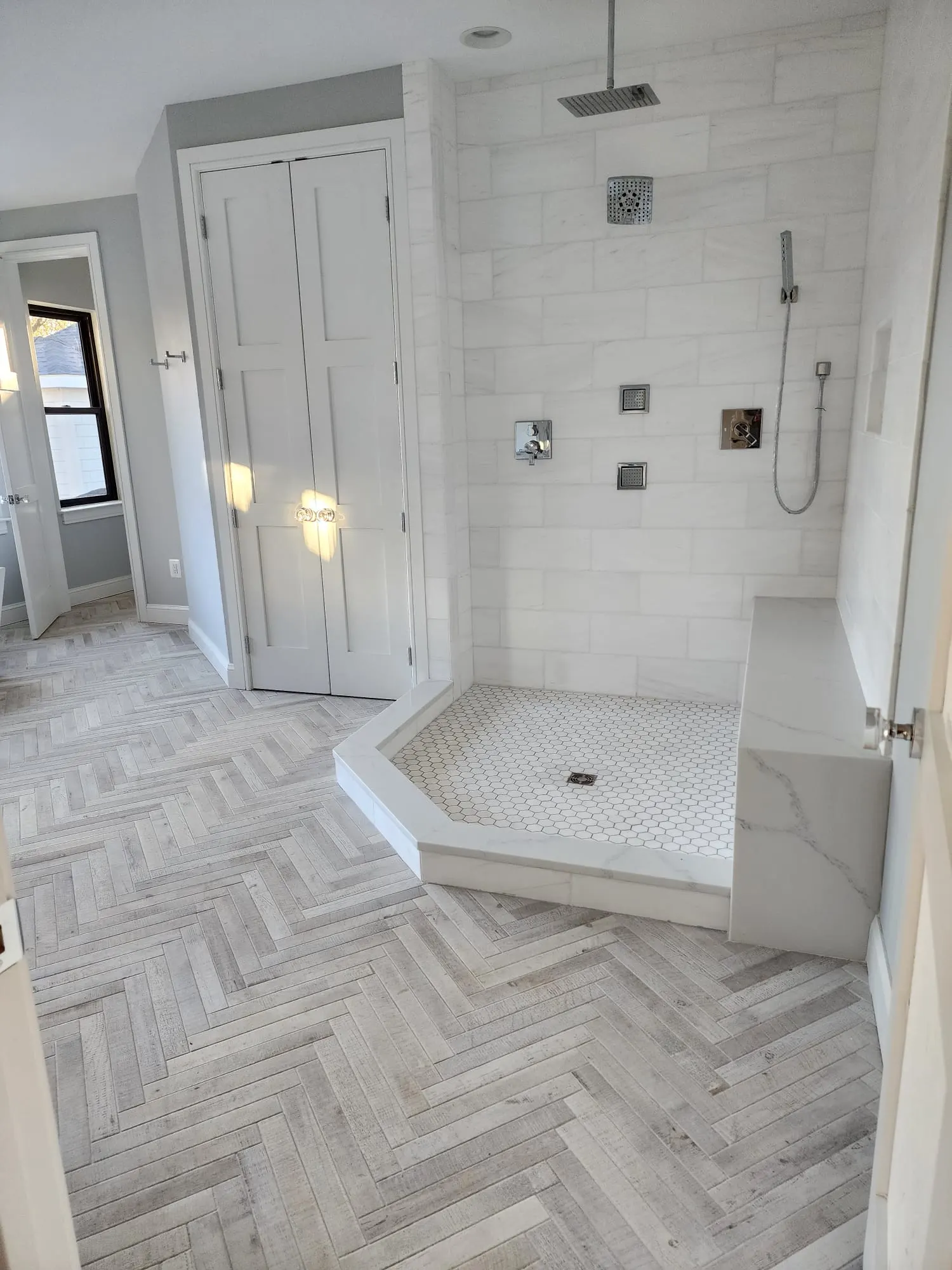 Walk-in shower with rain head, marble-look tile, and quartz bench