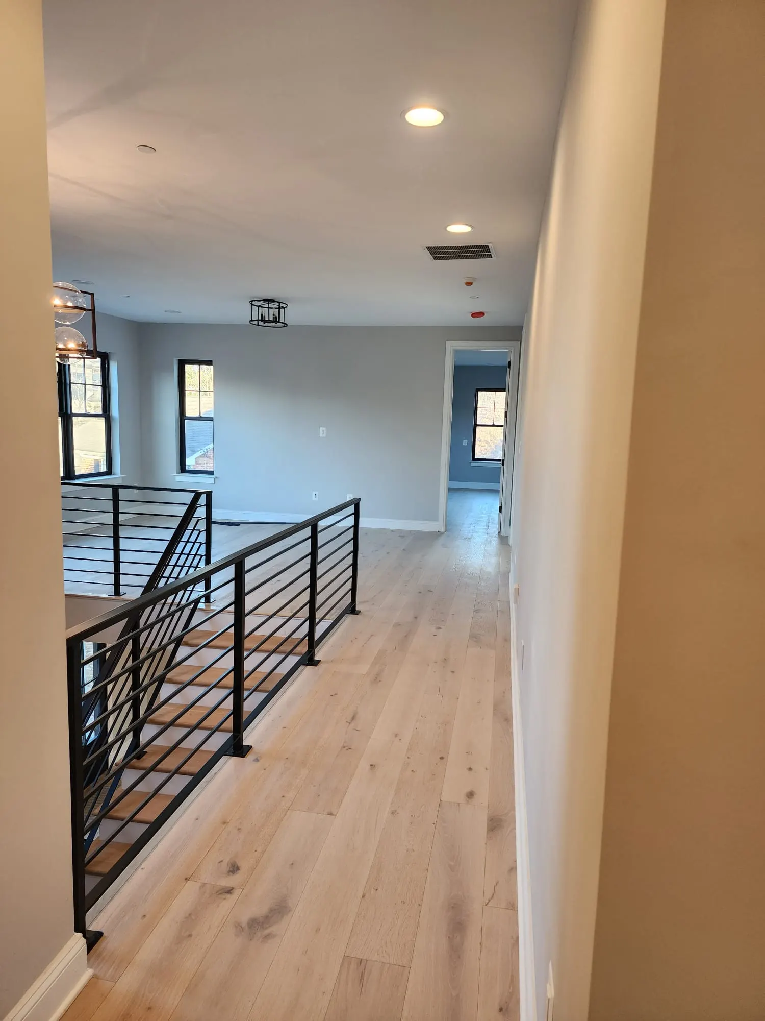 Upstairs landing with black metal railing and wide-plank oak floors