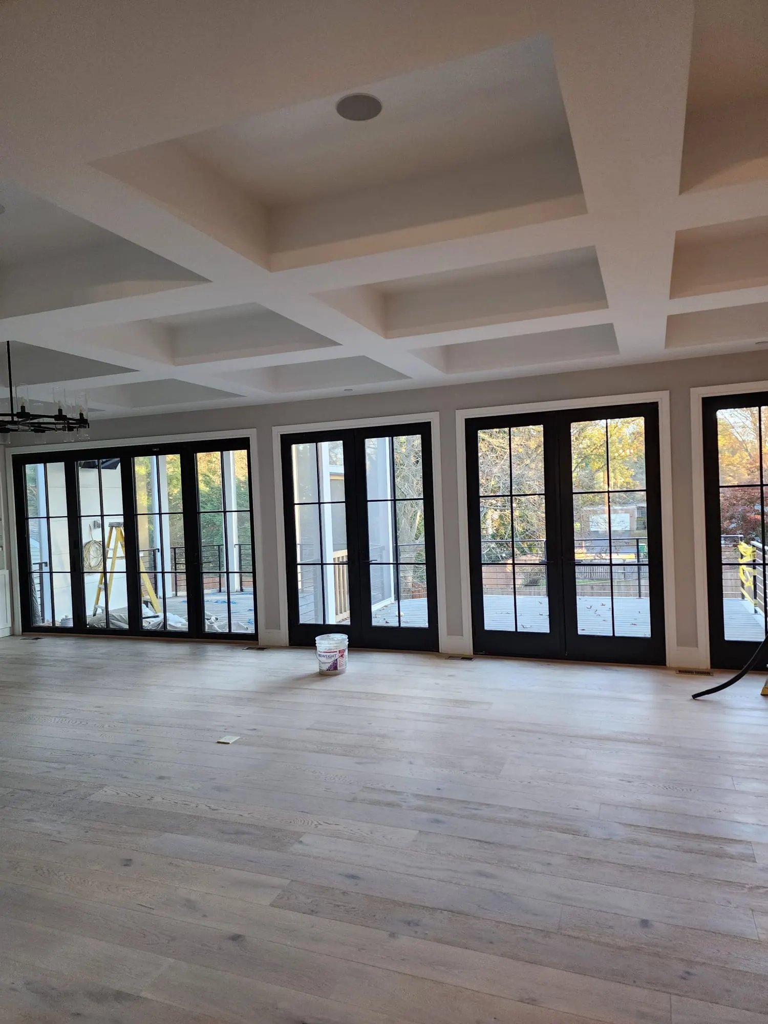 Great room with coffered ceiling and wall of black French doors