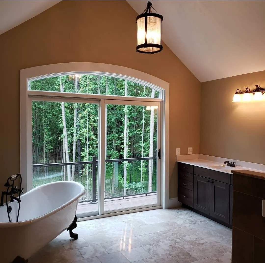 Bathroom with clawfoot tub and sliding door to wooded deck