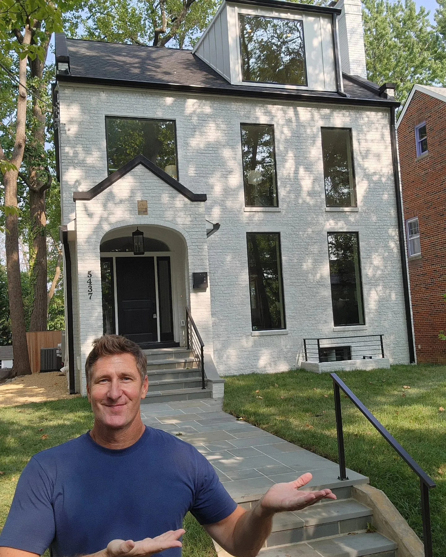 Kevin Slezak in front of a completed Colonial build, a white-painted brick two-story home